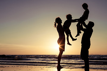 Image showing Silhouette of happy family who playing on the beach at the sunse