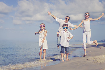 Image showing Father and children playing on the beach at the day time. 