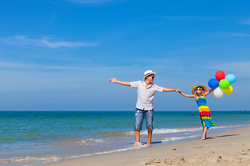 Image showing Father and daughter with balloons playing on the beach at the da