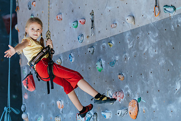 Image showing little girl climbing a rock wall indoor