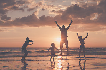 Image showing Father and children playing on the beach at the sunset time.