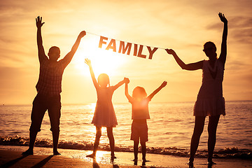 Image showing Happy family standing on the beach at the sunset time.