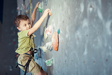 Image showing little boy climbing a rock wall indoor