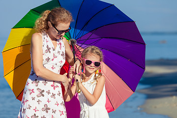 Image showing Mother and daughter playing with umbrella on the beach at the da