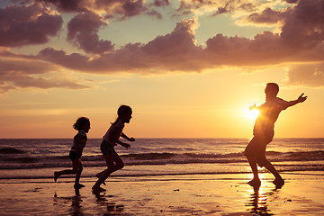 Image showing Father and children playing on the beach at the sunset time.