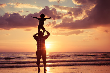 Image showing Father and son playing on the beach at the sunset time.