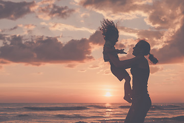 Image showing Mother and son playing on the beach at the sunset time.