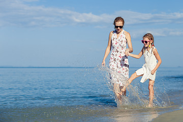 Image showing Mother and daughter playing  on the beach at the day time.