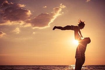 Image showing Father and son playing on the beach at the sunset time.