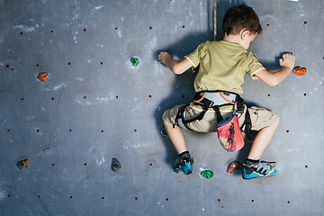 Image showing little boy climbing a rock wall indoor