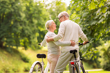 Image showing happy senior couple with bicycles at summer park