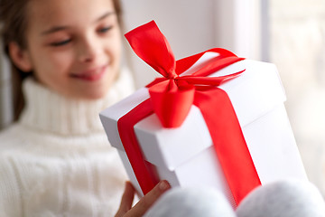 Image showing girl with christmas gift sitting on sill at home