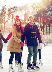 Image showing happy friends ice skating on rink outdoors