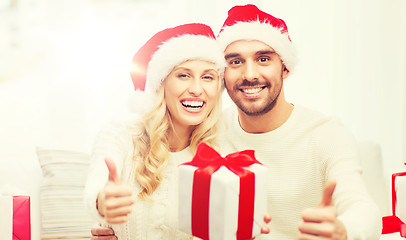 Image showing happy couple with christmas gifts and thumbs up