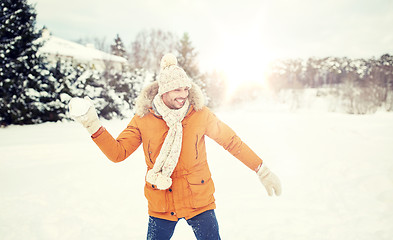 Image showing happy young man playing snowballs in winter