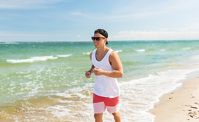 Image showing happy man running along summer beach