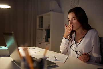 Image showing tired woman with papers yawning at night office