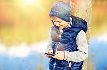 Image showing happy boy playing game on smartphone outdoors