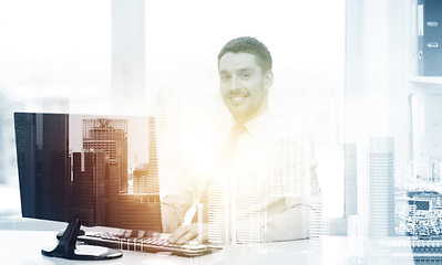 Image showing smiling businessman with computer at office