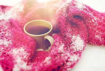 Image showing close up of tea or coffee and winter scarf in snow