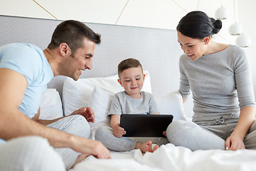 Image showing happy family with tablet pc in bed at home