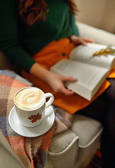 Image showing Cup of cappuccino and girl reading a book