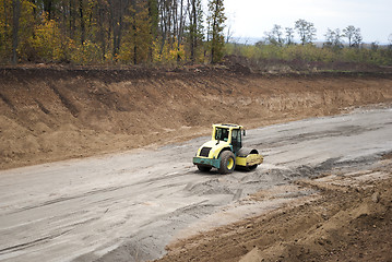 Image showing asphalt paver rolls out crushed stone