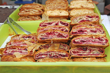 Image showing Sliced homemade strudel with cherry in streat market