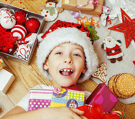 Image showing little cute boy with Christmas gifts at home. close up emotional happy smiling in mess with toys, lifestyle holiday people concept