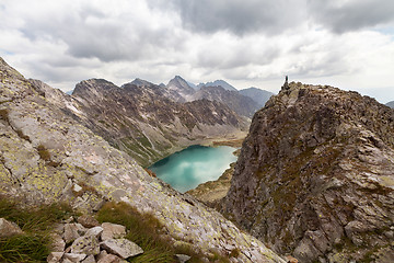 Image showing Hiking woman standing on high peak and pointing on rocky Tatra mountains