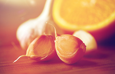 Image showing close up of garlic and orange on wooden table