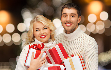 Image showing happy couple in sweaters holding christmas gifts