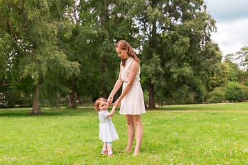 Image showing happy mother playing with baby girl at summer park