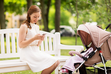 Image showing happy mother with smartphone and stroller at park