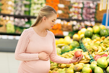 Image showing happy pregnant woman with pomegranate at grocery