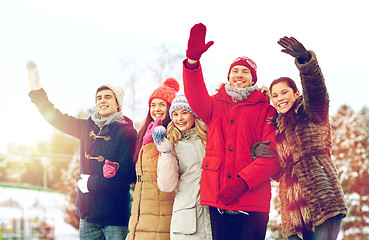 Image showing happy friends waving hands outdoors