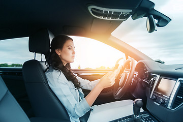 Image showing woman driving car with smarhphone