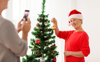 Image showing happy senior woman decorating christmas tree