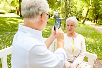 Image showing old man photographing woman by smartphone in park