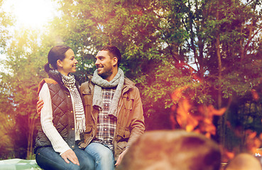 Image showing happy couple sitting on bench near camp fire