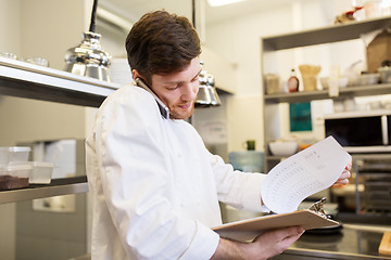 Image showing chef cook calling on smartphone at restaurant kitchen