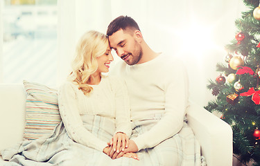 Image showing happy couple covered with plaid on sofa at home