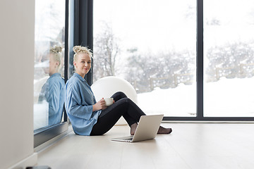 Image showing woman drinking coffee and using laptop at home