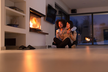 Image showing happy multiethnic couple sitting in front of fireplace