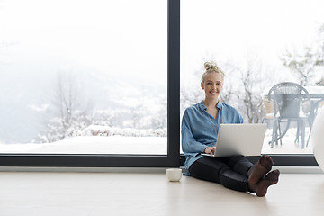 Image showing woman drinking coffee and using laptop at home