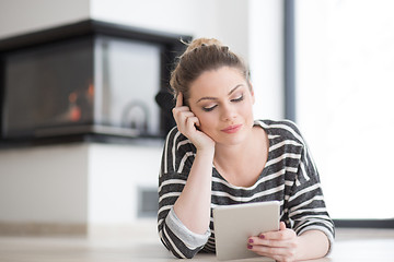 Image showing woman using tablet computer in front of fireplace