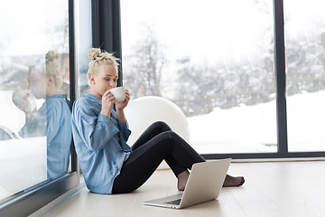 Image showing woman drinking coffee and using laptop at home