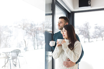 Image showing multiethnic couple enjoying morning coffee by the window