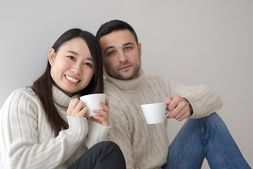 Image showing multiethnic couple enjoying morning coffee by the window