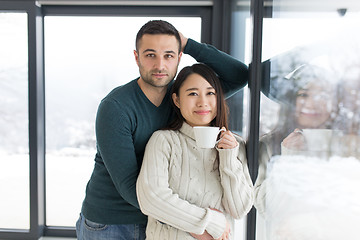 Image showing multiethnic couple enjoying morning coffee by the window